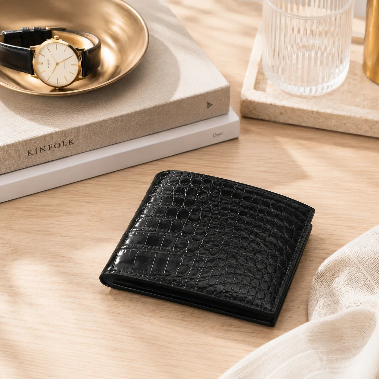 Calzoleria Toscana Italian crocodile leather wallets in cognac and black on a cream linen surface.