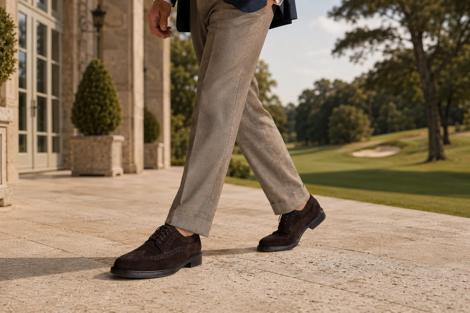 Well-dressed man in a charcoal three-piece Italian wool suit seated in a Tuscan library wearing handcrafted brown hand-burnished full-brogue wingtip oxford shoes by Calzoleria Toscana