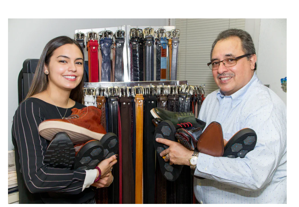 Father and daughter of the Toscana family in their showroom surrounded by handcrafted leather goods