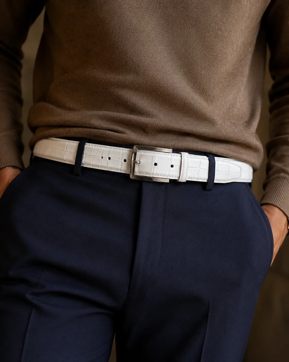 Man in a brown sweater and navy trousers wearing a Calzoleria Toscana white crocodile dress belt.