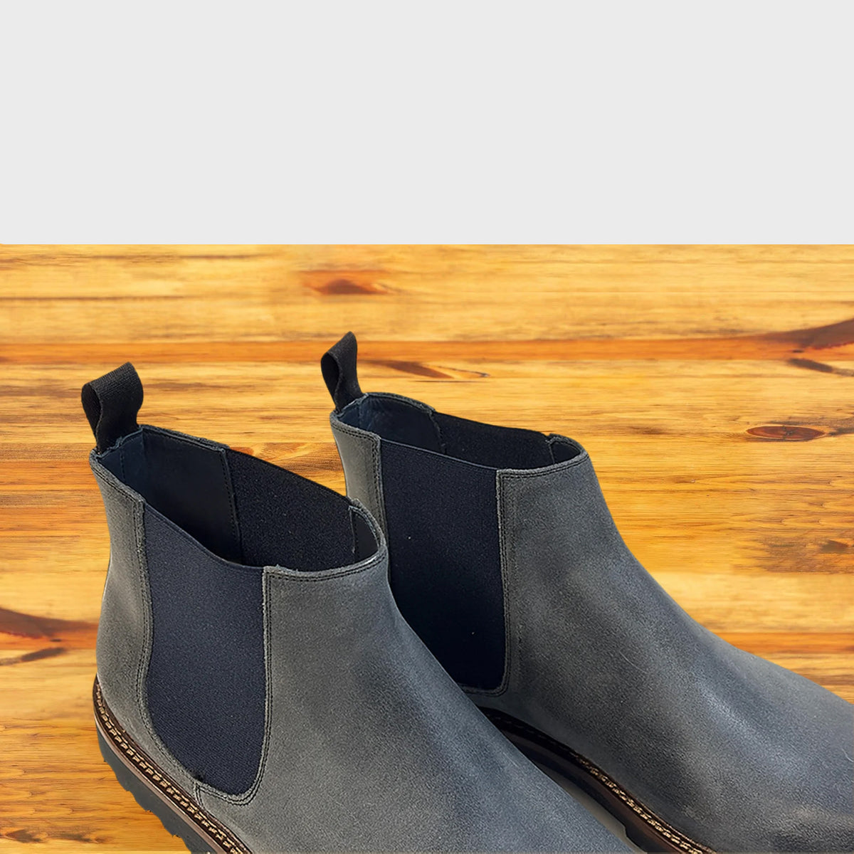 Pair of Stone leather Chelsea boots on a wooden surface