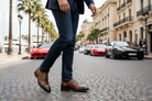 Person wearing a suit and shoes on a city street with cars and palm trees in the background