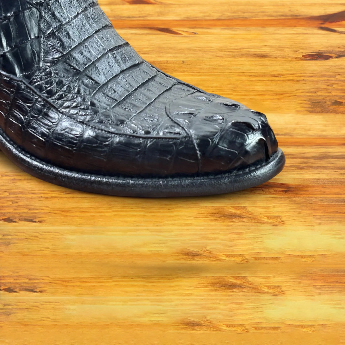 Black crocodile western boot on a wooden surface