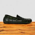 Green genuine crocodile leather loafer on a wooden surface with a light gray background