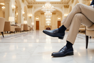Person wearing blue dress shoes and beige pants in a luxurious interior setting.