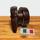 Tobacco leather belt with silver buckle on a wooden surface, accompanied by a 'Made in Italy' label.