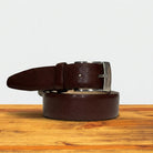 Tobacco leather belt with silver buckle on a wooden surface