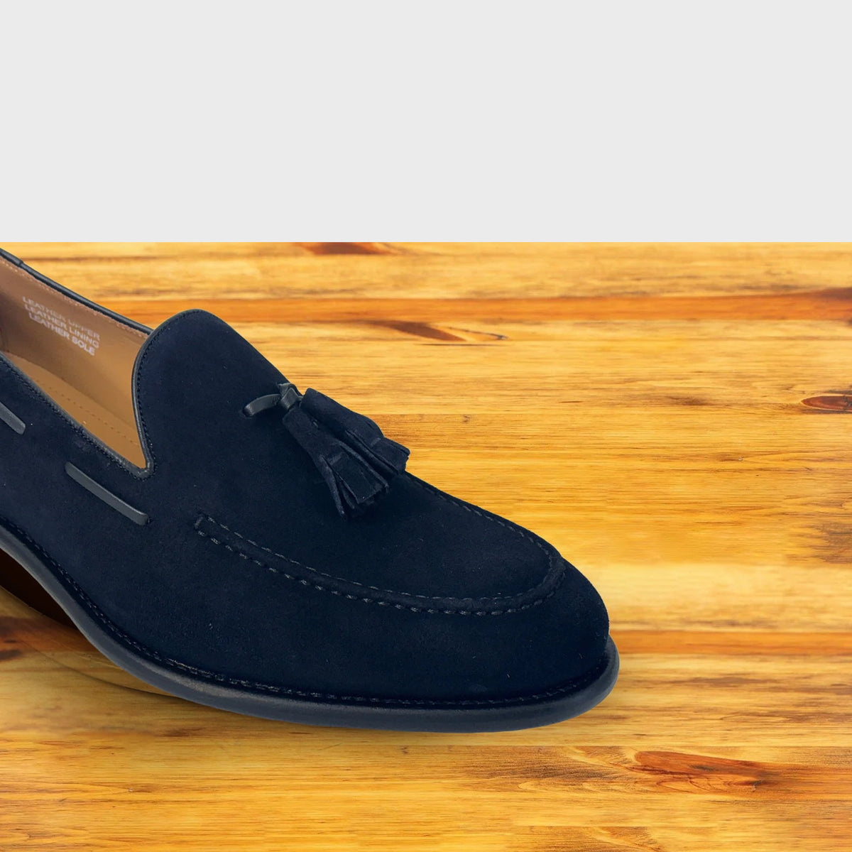 Blue loafer with a tassel on a wooden surface