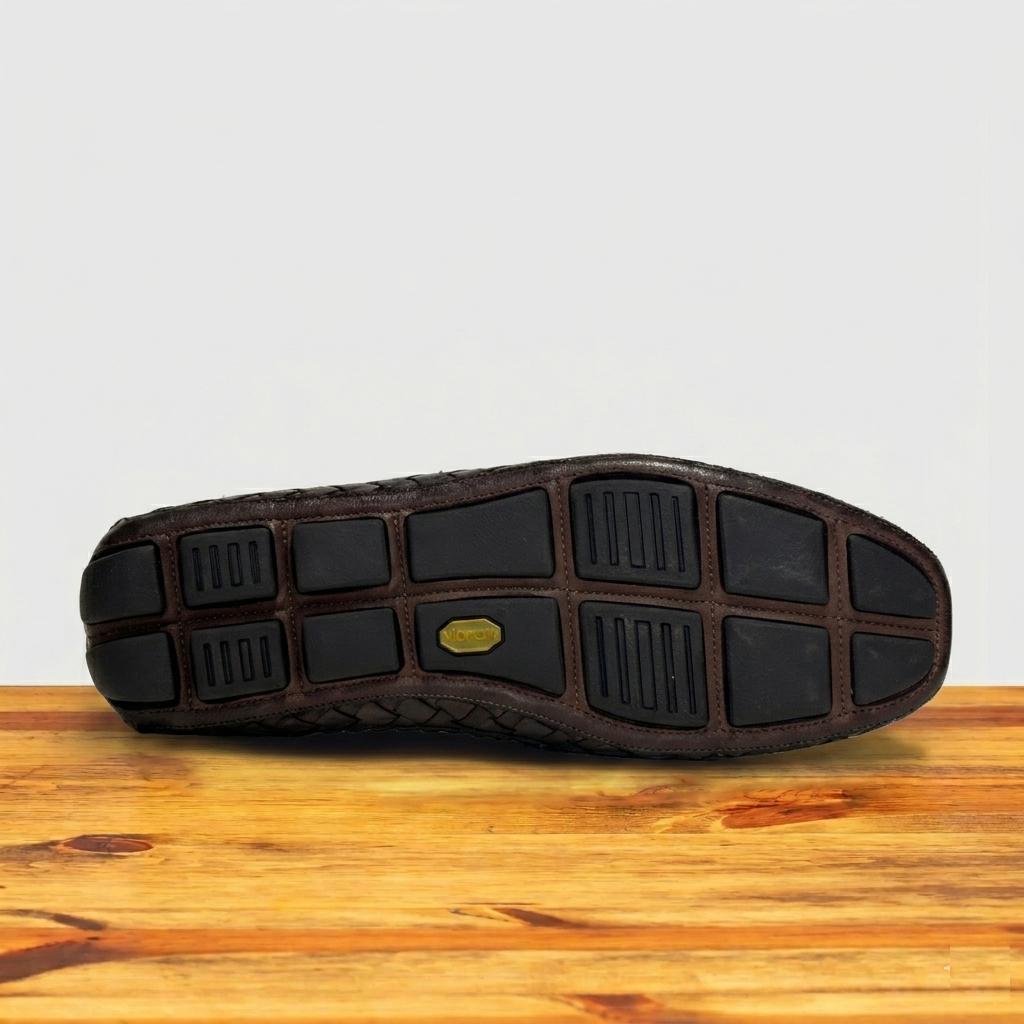 Dark Brown shoe sole on a wooden surface with a light gray background