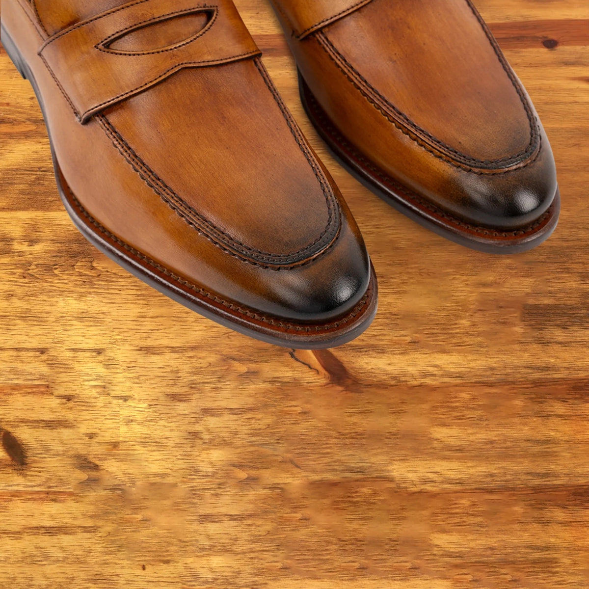 A Pair of Dark Caramel leather loafer on a wooden surface