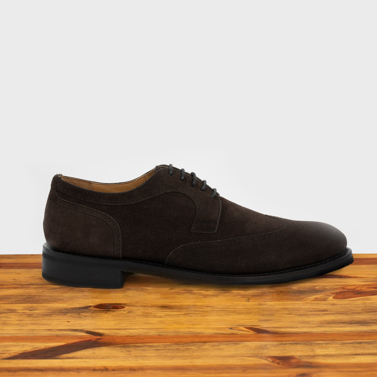 Dusty Brown suede dress shoe on a wooden surface with a light gray background