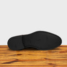 Outsole of the Dusty Brown suede dress shoe on a wooden surface with a light gray background