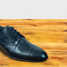 Black leather dress shoe on a wooden surface
