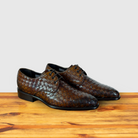 Pair of Mahogany woven leather shoe on a wooden surface with a light gray background