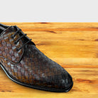 Mahogany woven leather shoe on a wooden surface