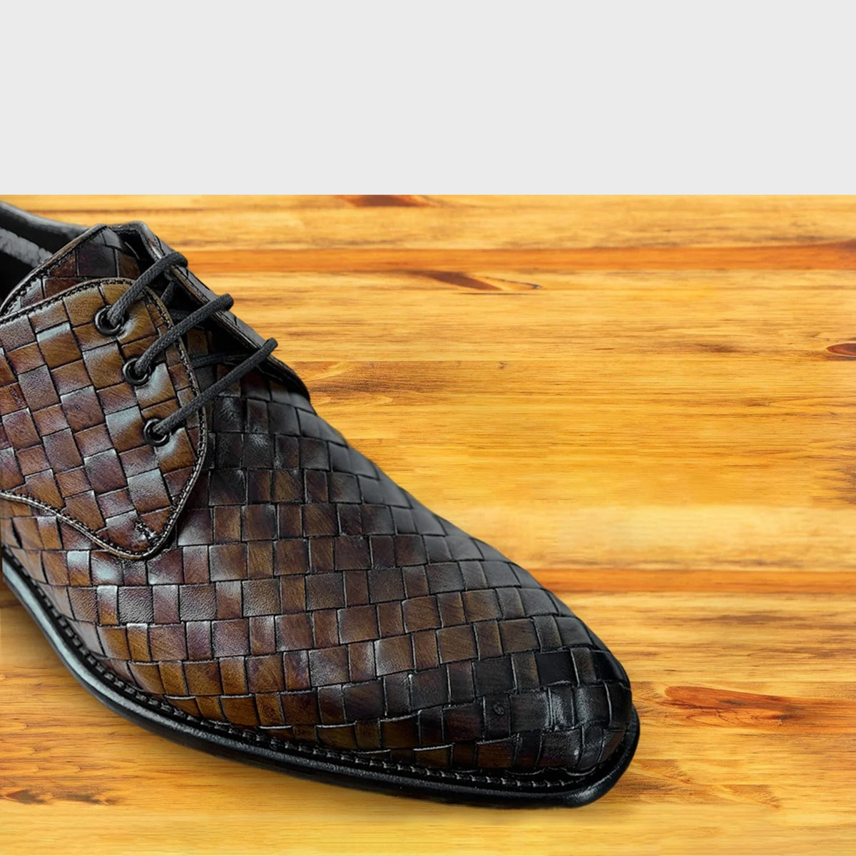 Mahogany woven leather shoe on a wooden surface