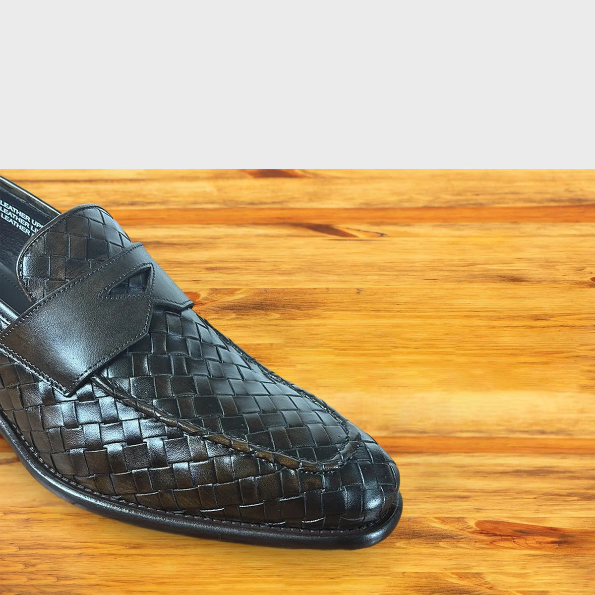 Close up of Dark Brown woven loafer shoe on a wooden surface