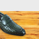 Close up of Emerald Green woven loafer shoe on a wooden surface