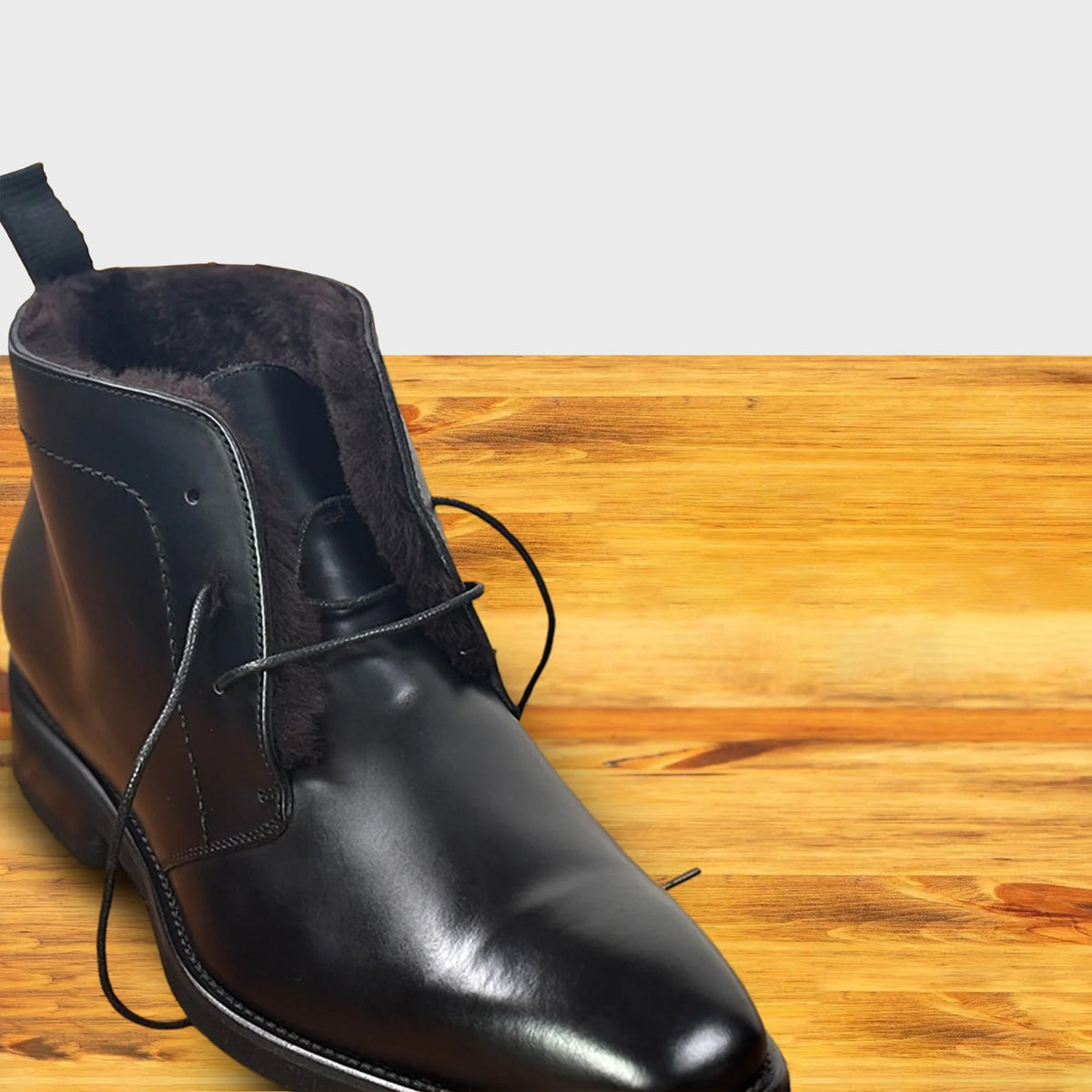 Black leather boot on a wooden surface