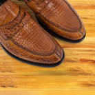 A pair of brick loafers with black soles, displayed on a light wood plank surface.