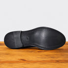 Black leather shoe sole on a wooden surface with a light gray background