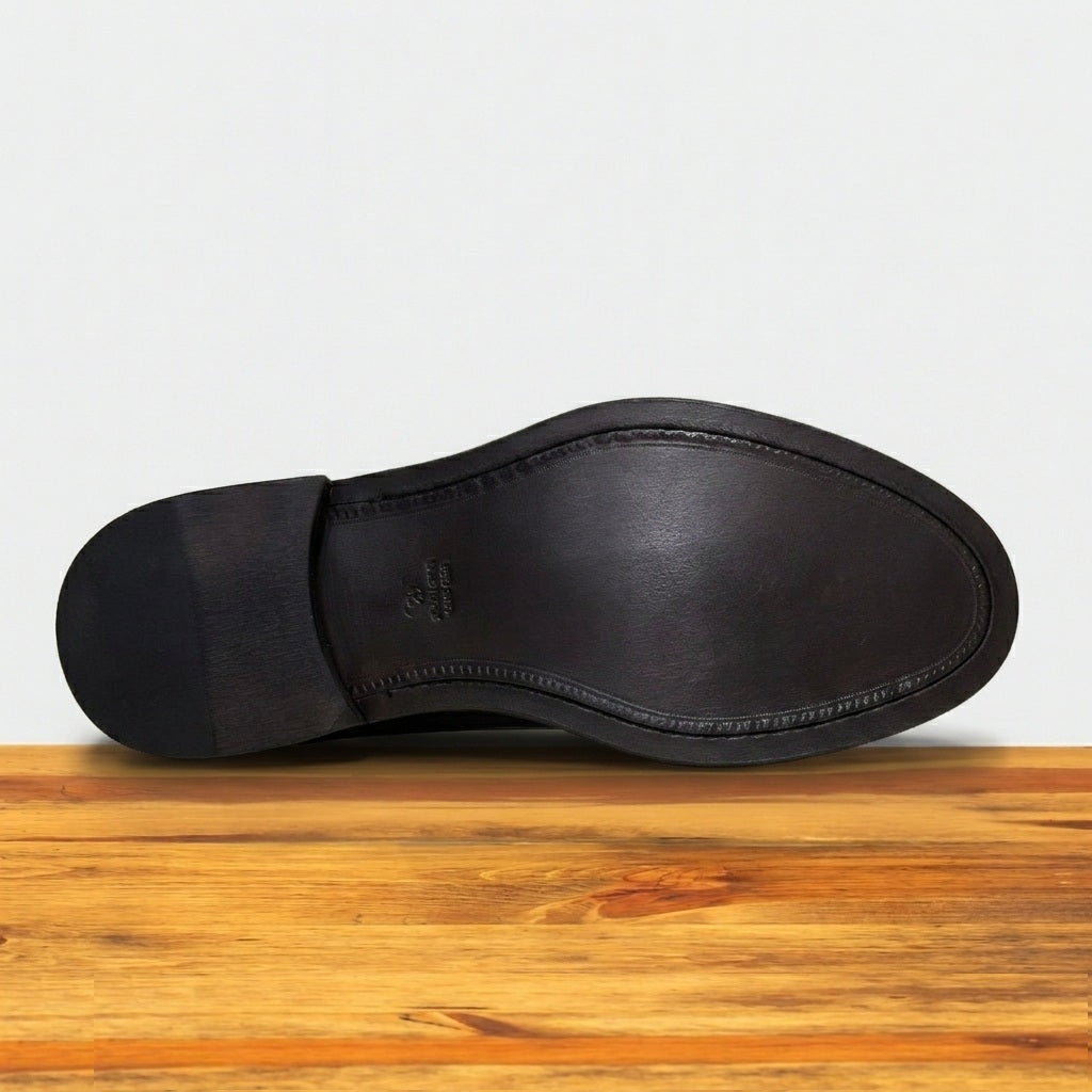 Tobacco leather shoe Outsole on a wooden surface with a light gray background