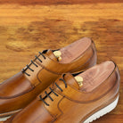Q907 Dark Caramel leather shoes, pair viewed from above showing the burnished finish, cedar shoe trees and white midsole on a wooden surface