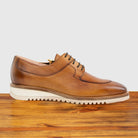 Dark Caramel leather shoe on a wooden surface with a light gray background