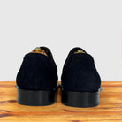 A pair of blue suede loafers shown from the back on a wooden surface against a light gray background.