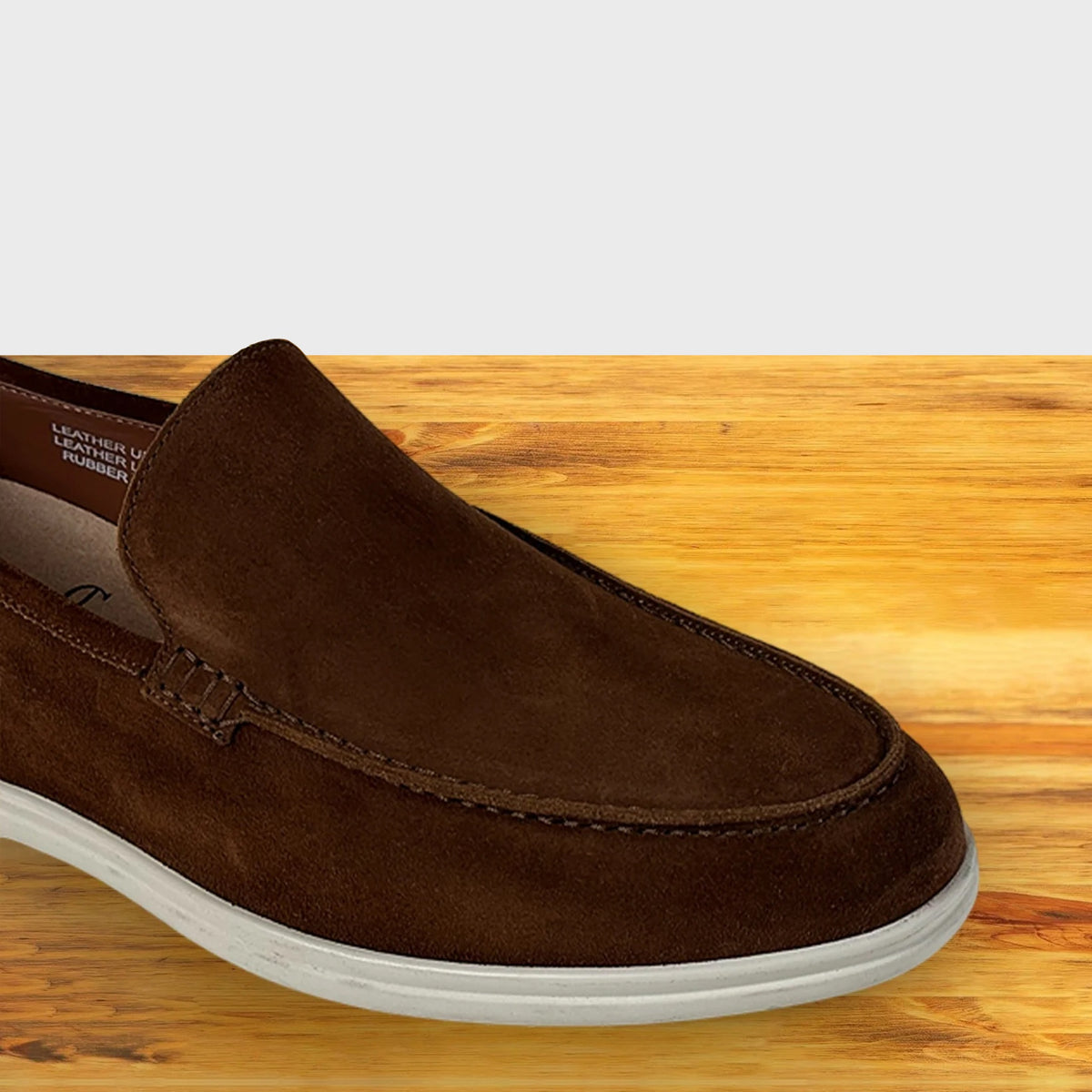 Brown suede loafer shoe on a wooden surface