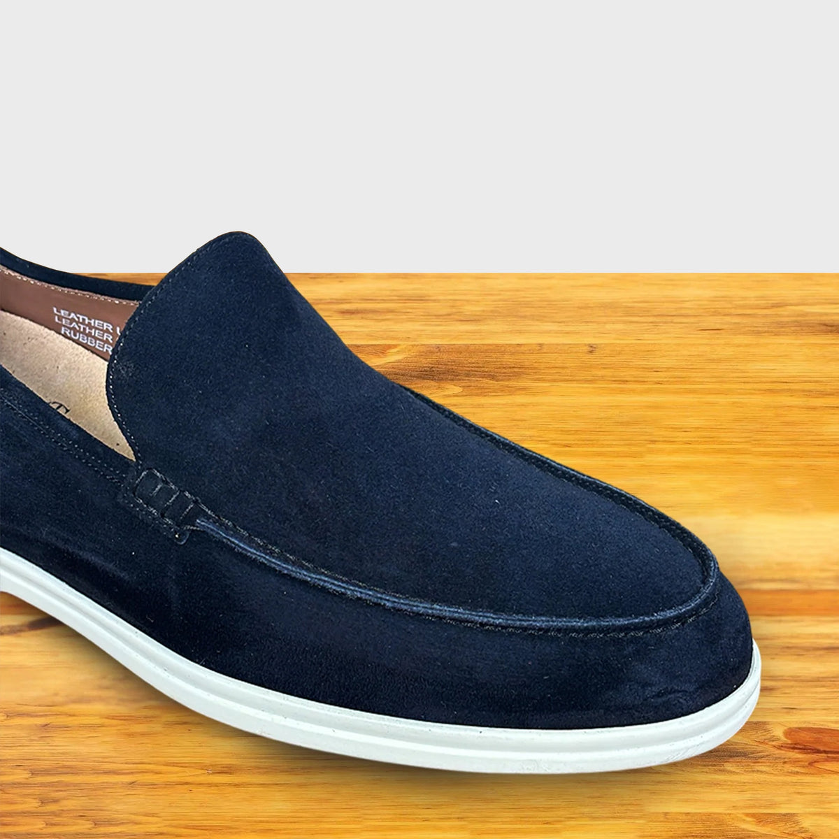 Navy Blue suede loafer shoe on a wooden surface