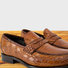 A pair of brick leather penny loafers resting on a wooden surface.