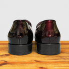 A pair of Burgundy patent leather slip-on dress loafers with black stacked heels, shown from the back.
