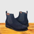 Navy blue Chelsea boot on a wooden surface.