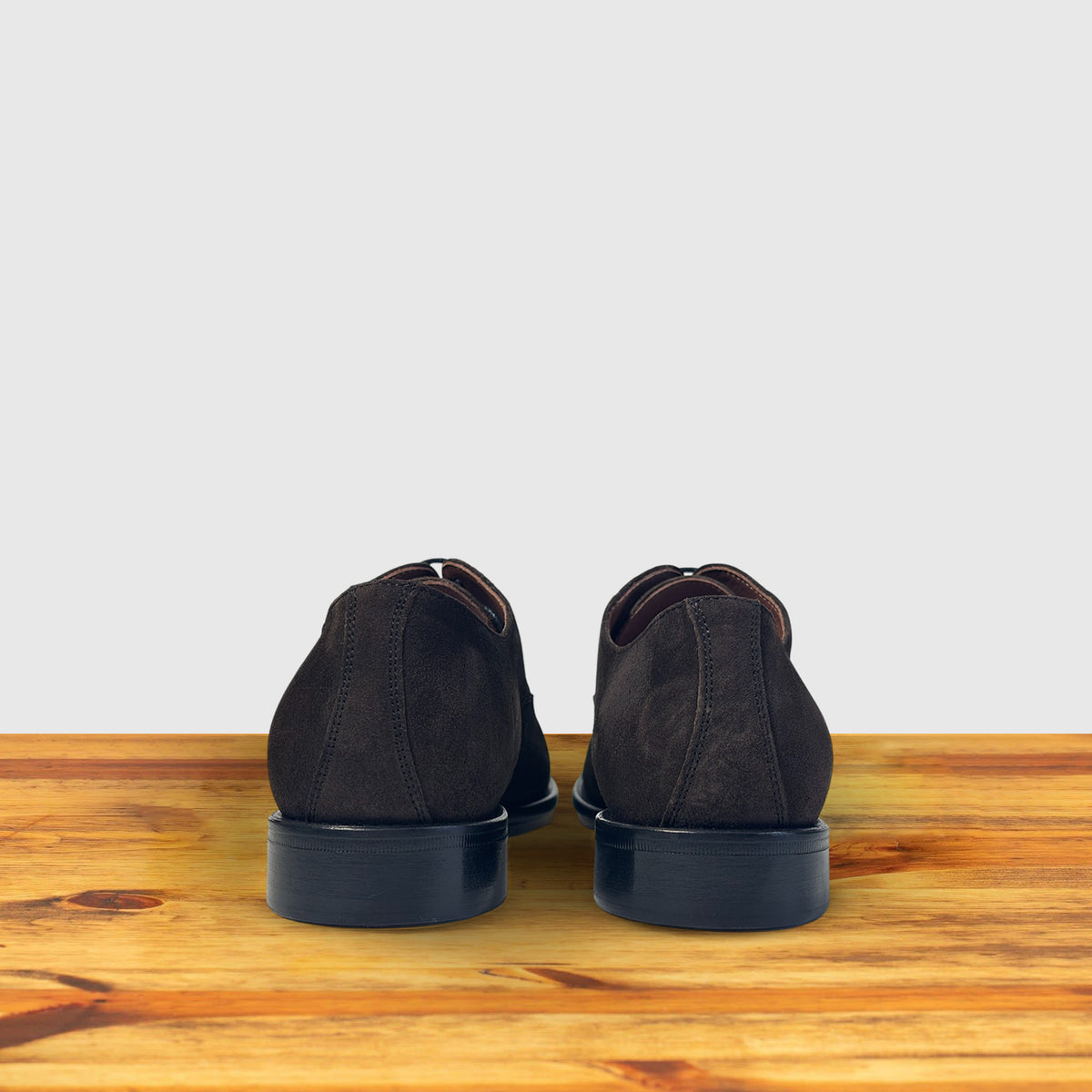 Dozza Dusty Brown suede oxford shoes, rear view of the pair showing the heel, dark suede finish and black leather sole on a wooden surface