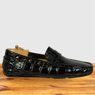 A single burgundy crocodile-embossed loafer shoe displayed on a wooden surface against a light gray background.