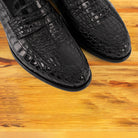 Black leather loafer on a wooden surface 