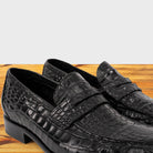 Black leather loafer on a wooden surface