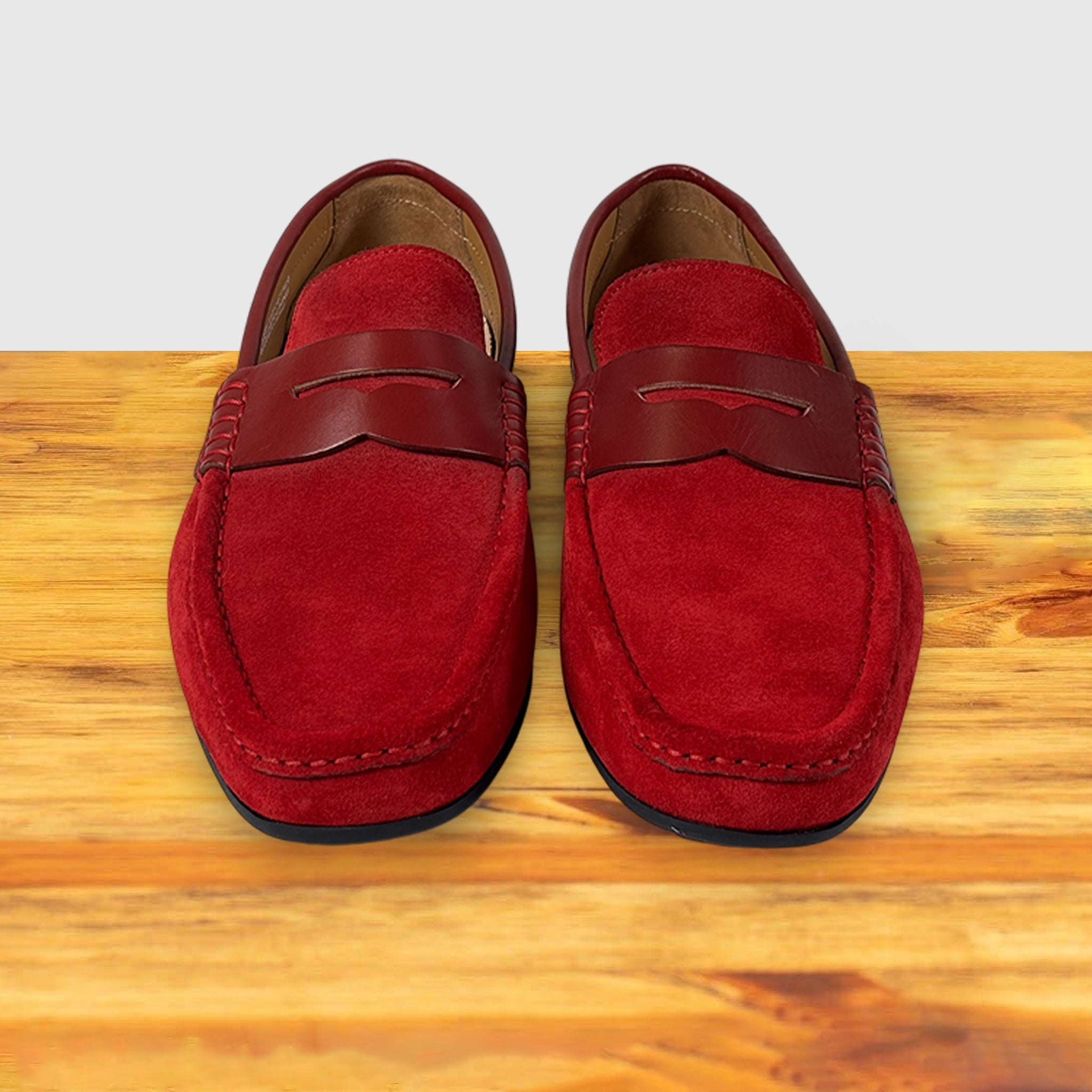 Pair of red loafers on a wooden surface with a light gray background