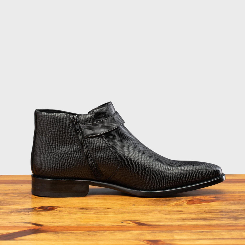 Side profile of the 1221 Calzoleria Toscana Saffiano Leather Black Ankle Zip Boot on top of a wooden table