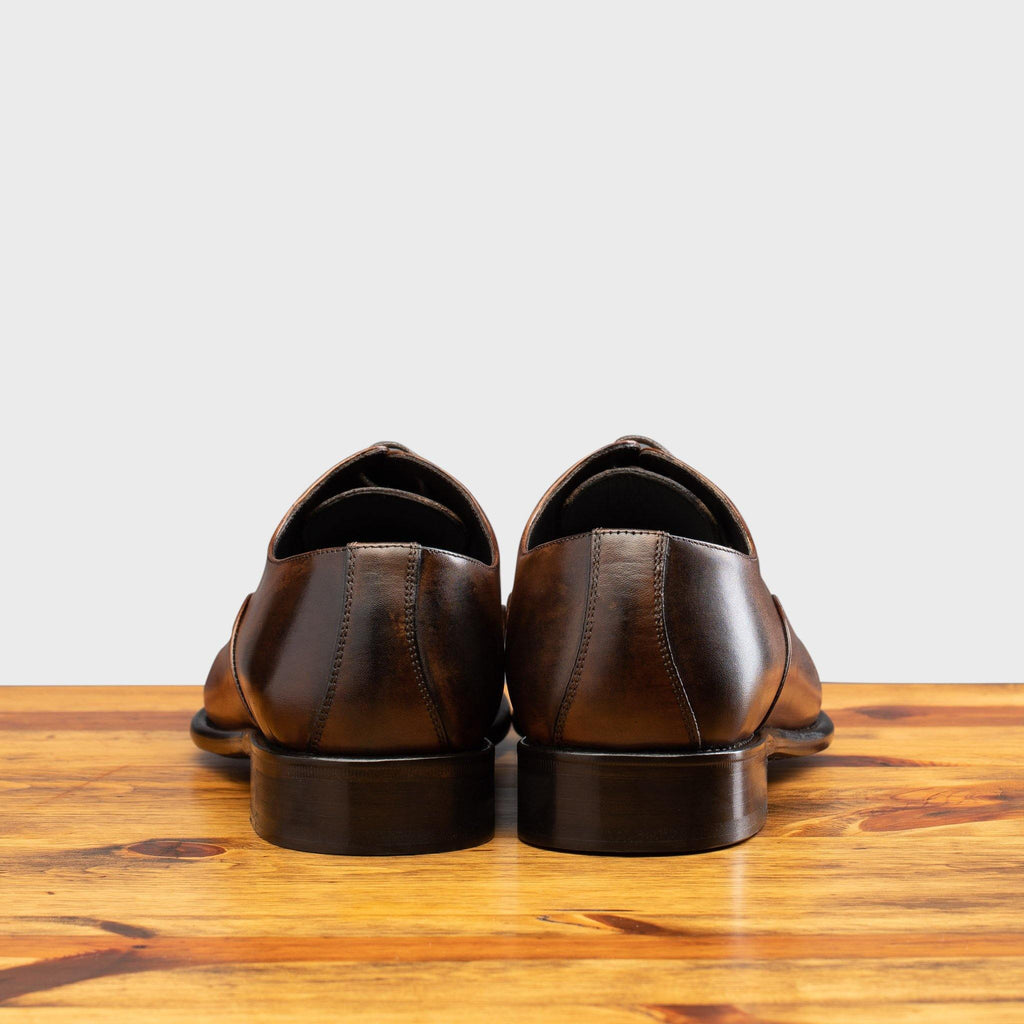 Back profile of the 2361 Calzoleria Toscana Brown Cayenne Calf Cap Toe on top of a wooden table