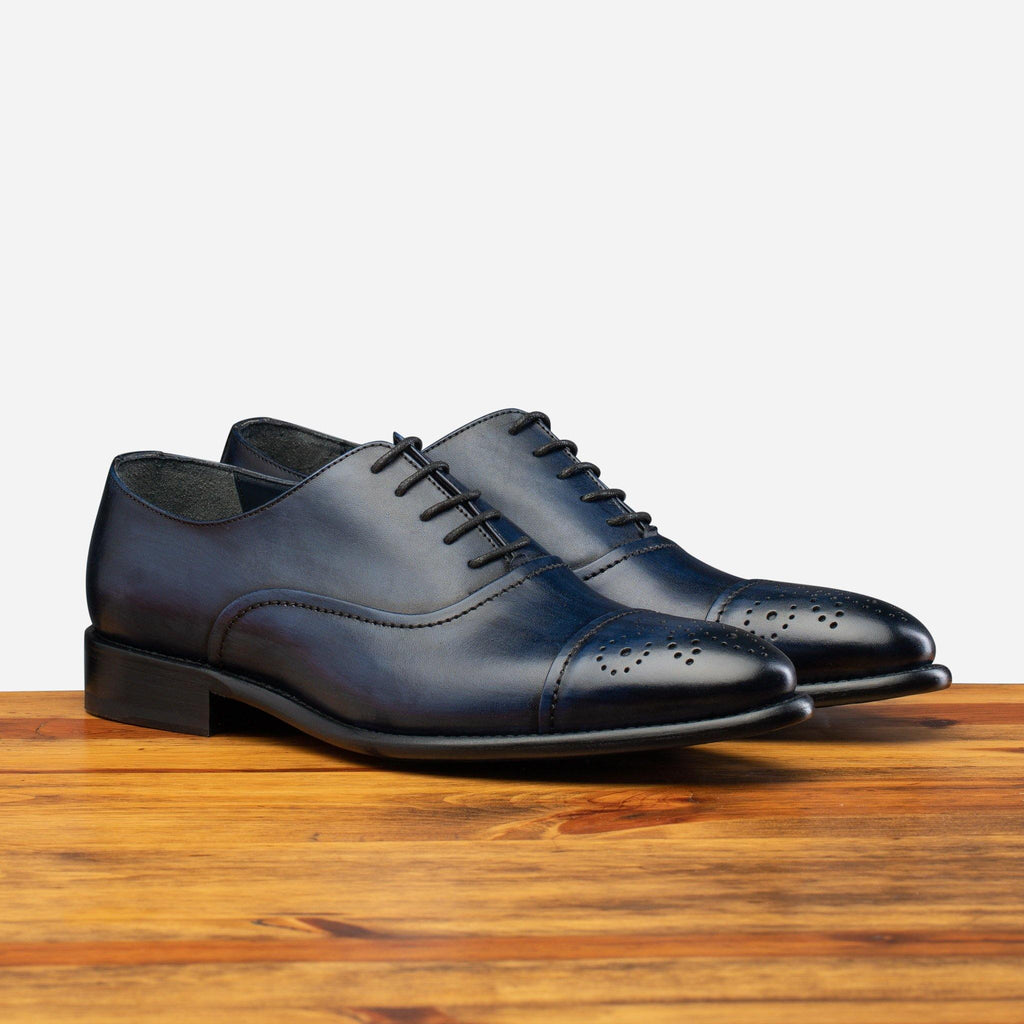 Pair of the  2361 Calzoleria Toscana Blue Cayenne Calf Cap-Toe on top of a wooden table
