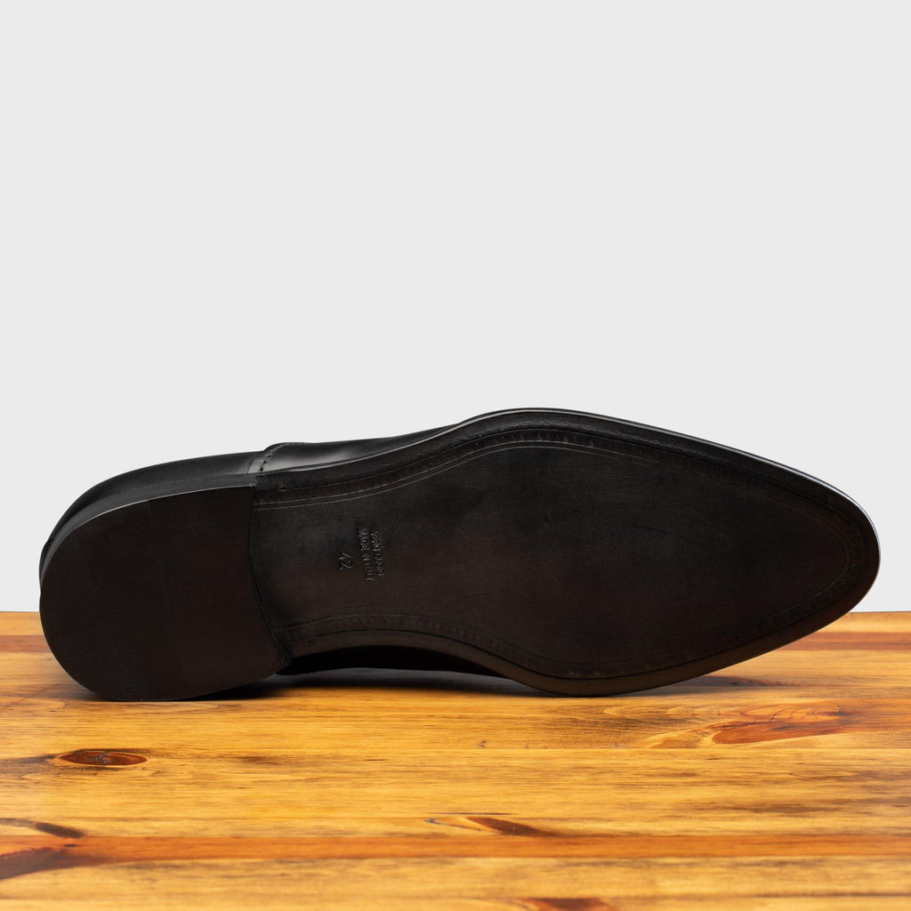 Full leather outsole of the 2361 Calzoleria Toscana Black Cayenne Calf Cap Toe on top of a wooden table