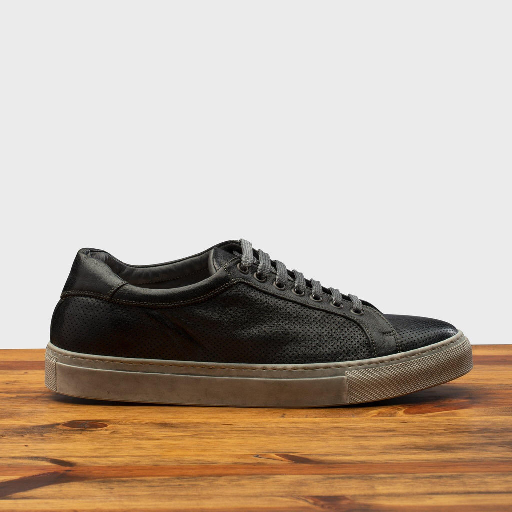 Side profile of the 3042 Calzoleria Toscana Black Benso sneaker on top of a wooden table