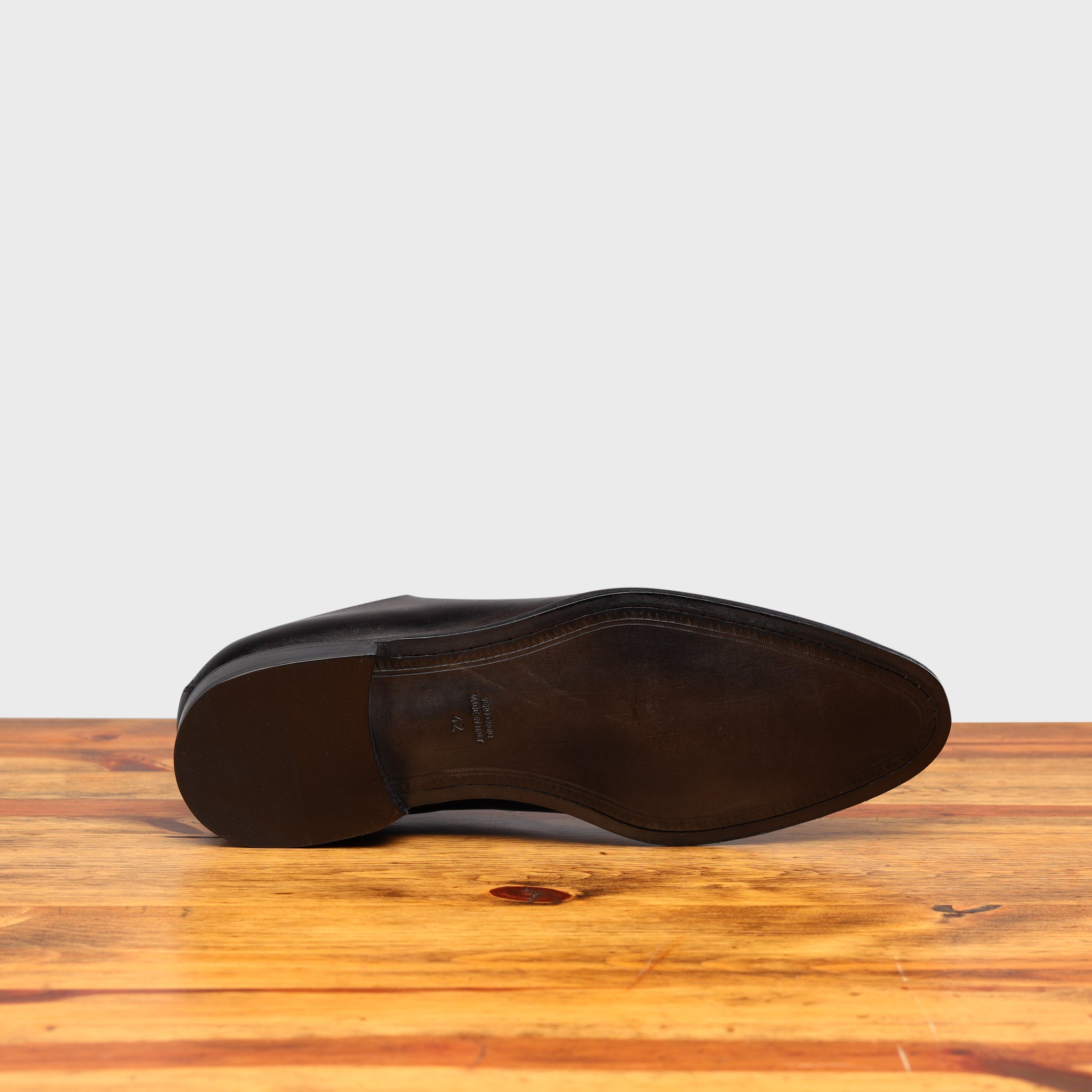 Full leather outsole of Q550 Calzoleria Toscana Graphite Cayenne Calf Wholecut on top of a wooden table