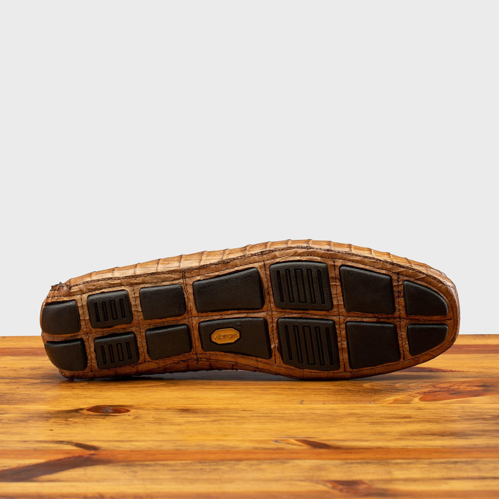 Full Rubber Vibram Outsole showing crocodile fully wrapped on the outsole  of 4551 Calzoleria Toscana Cerris Crocodile Dip-Dyed Driver on top of a wooden table
