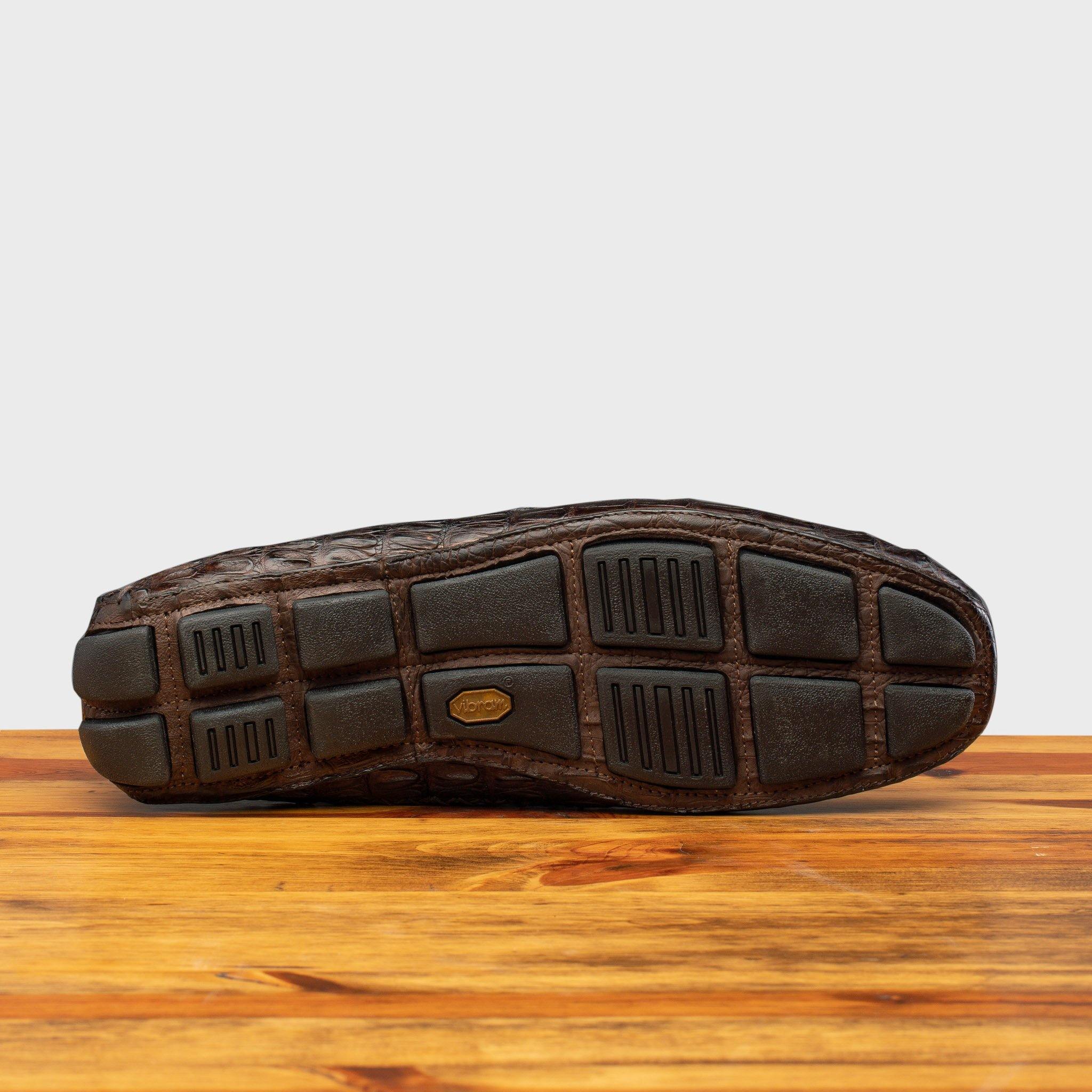 Full Rubber Vibram Outsole showing crocodile fully wrapped on the outsole of 4551 Calzoleria Toscana Dark Brown Crocodile Dip-Dyed Driver on top of a wooden table