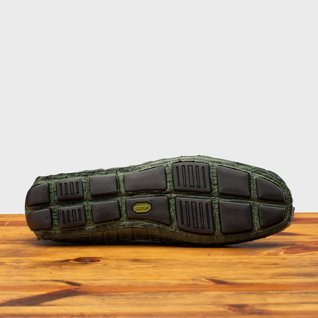 Full Rubber Vibram Outsole showing crocodile fully wrapped on the outsole of 4551 Calzoleria Toscana Green Crocodile Dip-Dyed Driver on top of a wooden table
