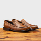 Pair of the 5034 Calzoleria Toscana Mahogany Crocodile Slip-On on top of a wooden table