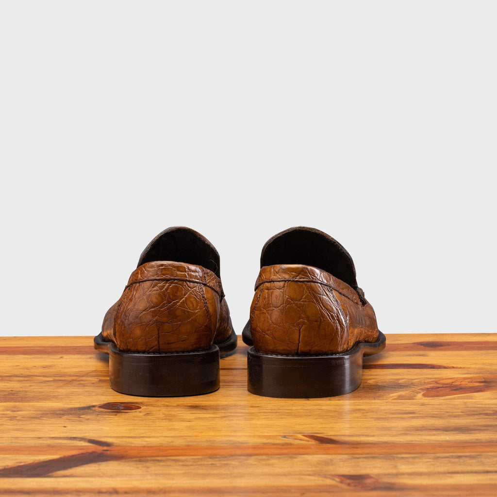 Back profile of 5034 Calzoleria Toscana Mahogany Crocodile Slip-On on top of a wooden table